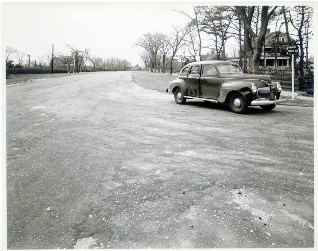 Montauk Highway and Quogue Street, looking west. “Narioch,” ca. 1890, on right, and “Bella-Mar,” on left. Designed by architect Isaac Green and built as a single home, ca. 1894, the house was split in the early 1960s (now 107 & 109 Quogue Street).